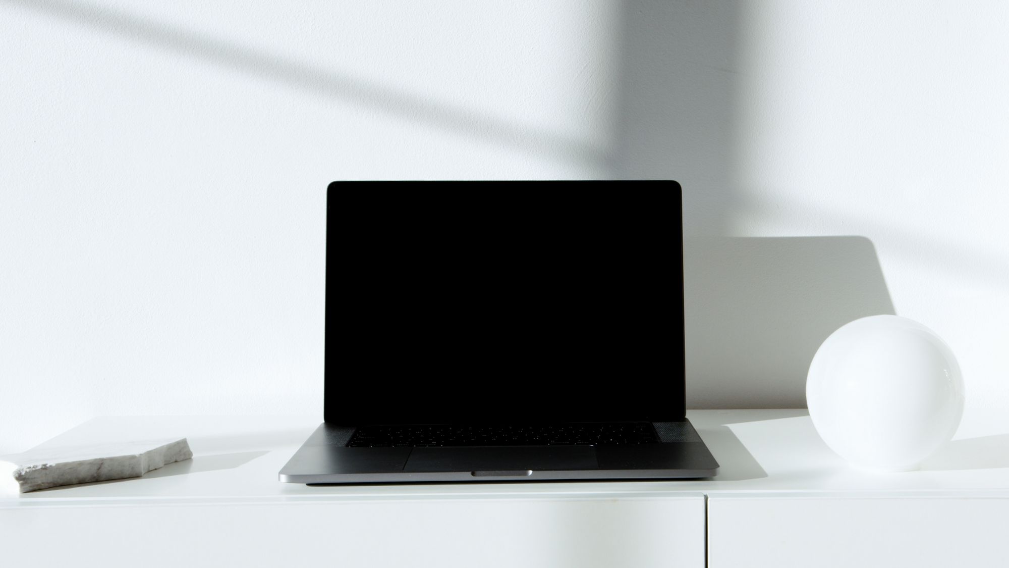 Minimal modern workspace with a laptop on a white desk